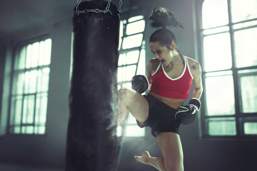 Young Athletic Woman Heavy Bag Flying Knee