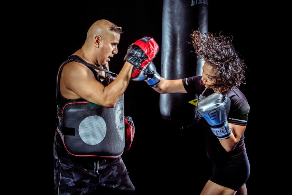 Woman Punching The Hand Of Man Wearing Training Gloves